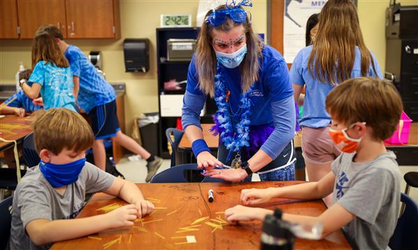 Students gather around a table to see classmates' spaghetti tower